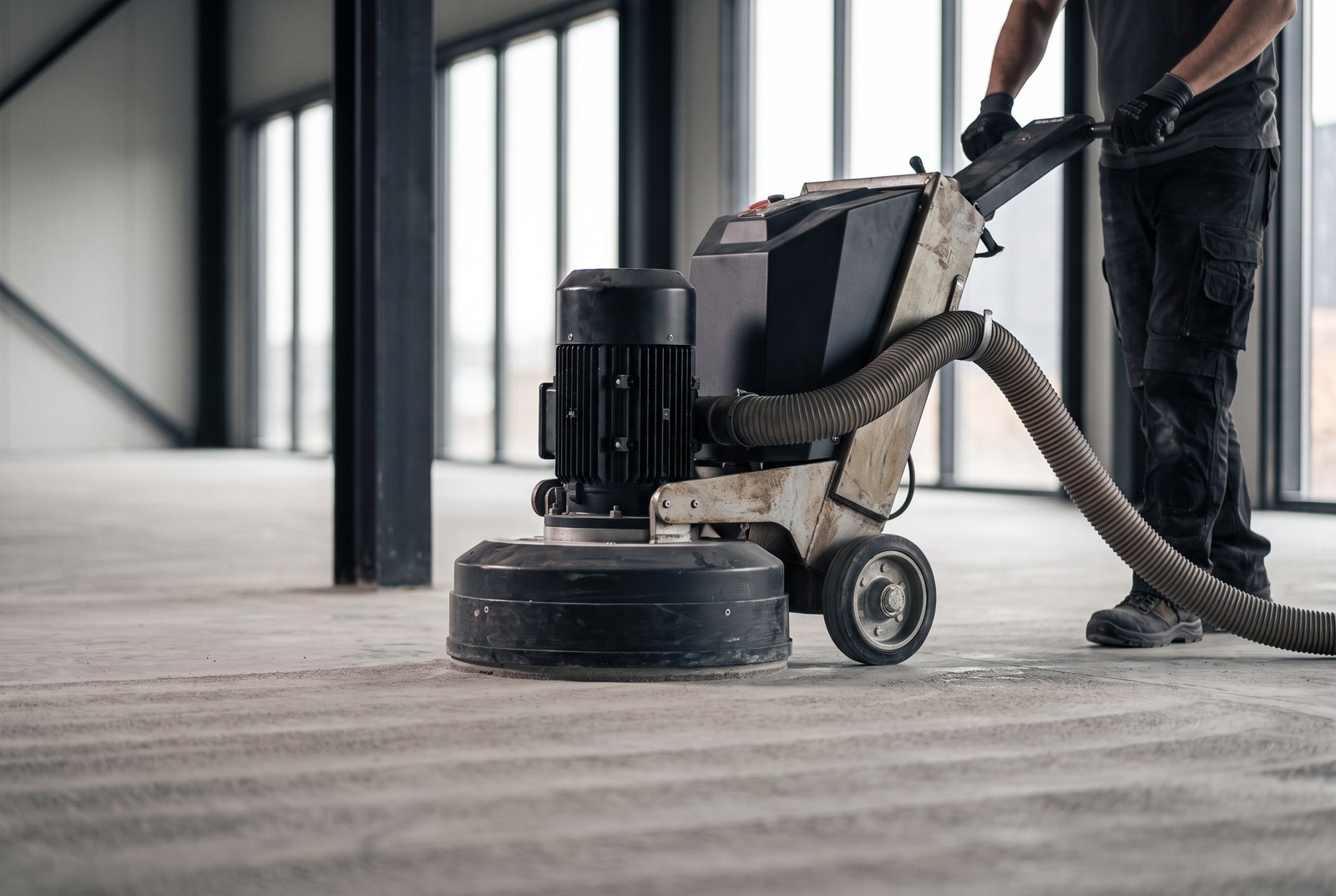 Illustrative concrete preparation with a floor grinder and dust extraction in an industrial interior